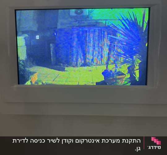 מסך אינטרקום מציג חצר עם צמחייה